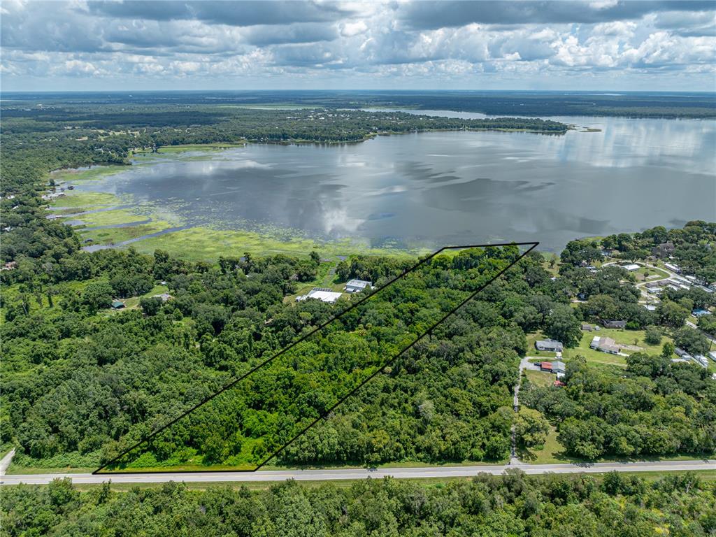 An aerial view shows a wooded plot of land bordering a large lake — 0 TIMBERLANE ROAD, LAKE WALES, FL