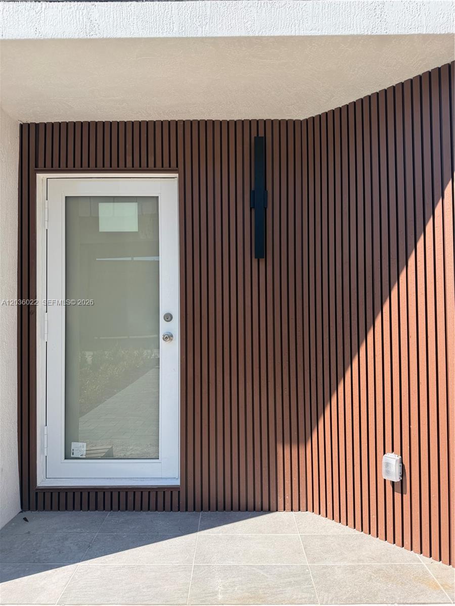 A white door is set into a wall covered with vertical brown wood slats — 1629 NW 40th St, Miami FL 33142, MIAMI, FL