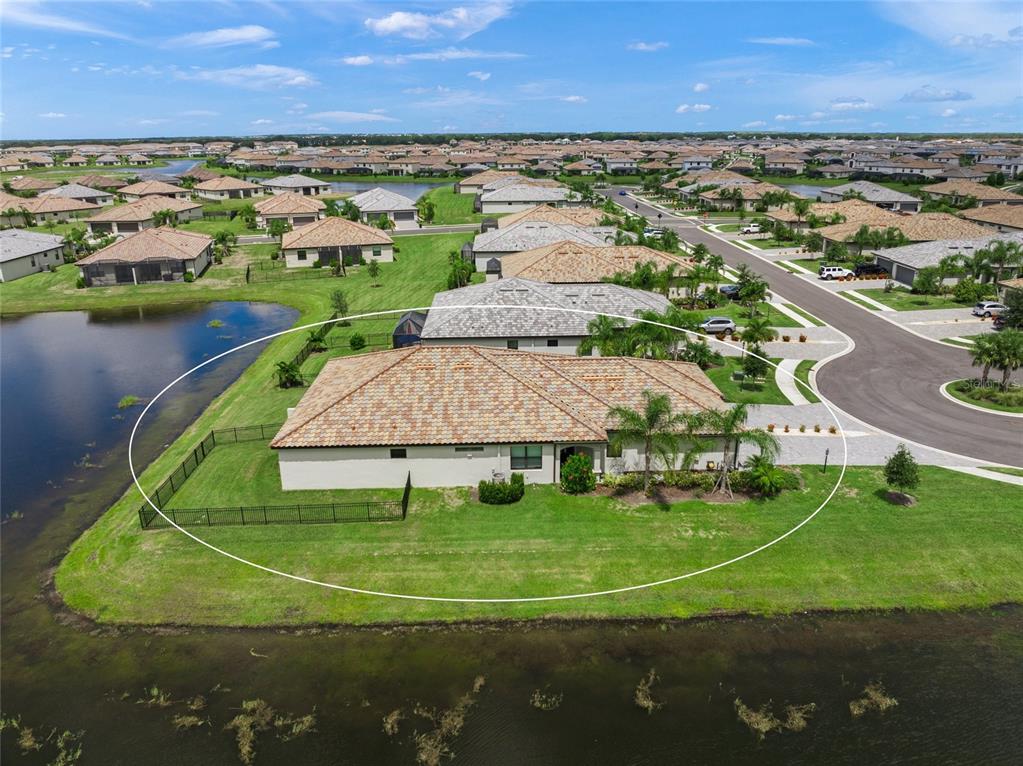 An aerial view shows a single-story house with a tiled roof situated beside a pond — 15982 CLEAR SKIES PLACE, BRADENTON, FL