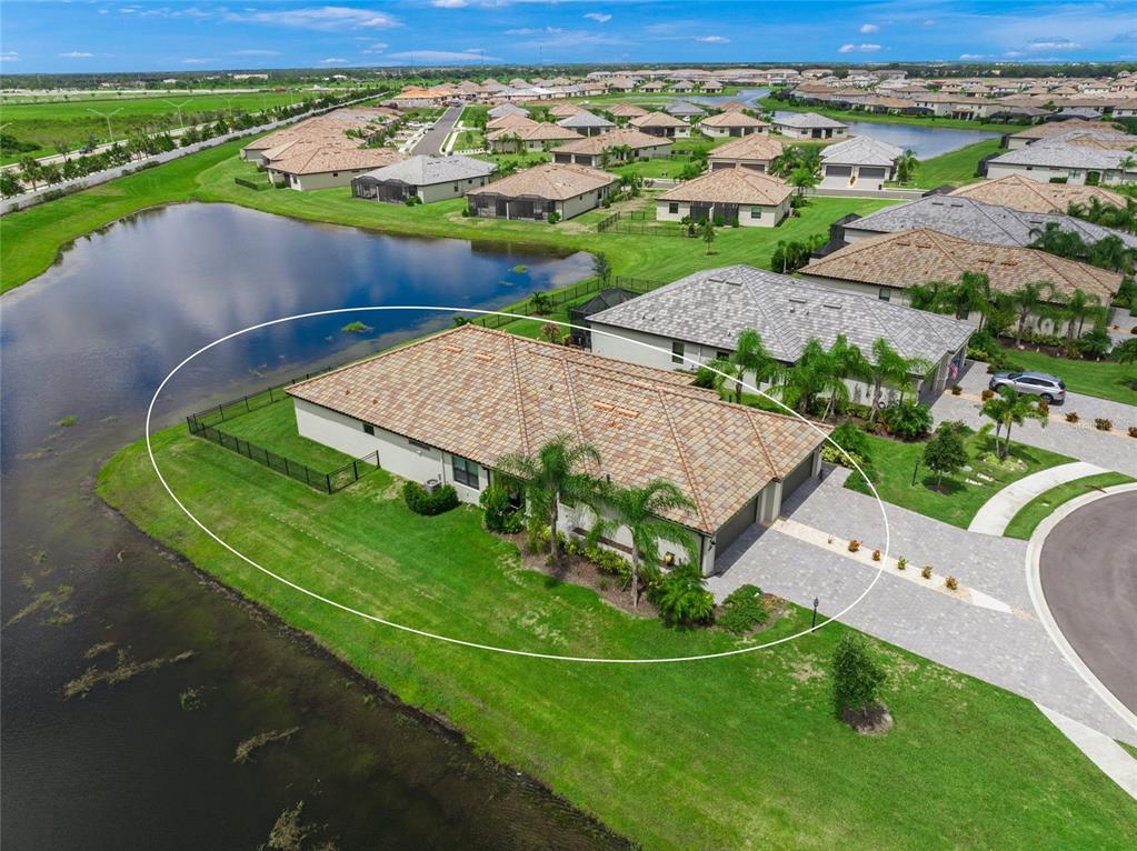 An aerial view of a single-story house with a tiled roof situated beside a pond — 15982 CLEAR SKIES PLACE, BRADENTON, FL