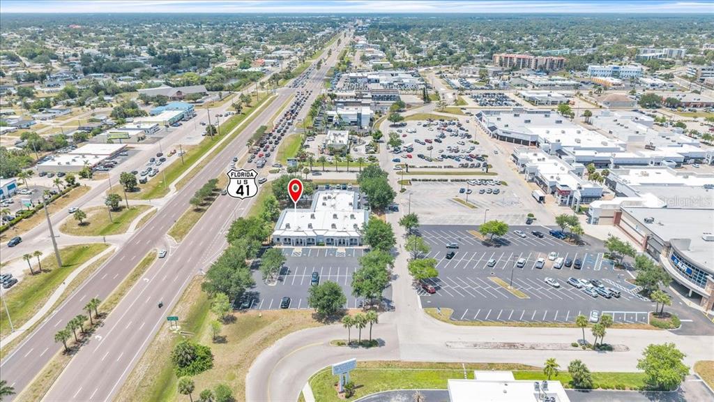 This aerial view shows a commercial building with a parking lot next to a highway — 3300 TAMIAMI TRAIL UNIT 2, PORT CHARLOTTE, FL