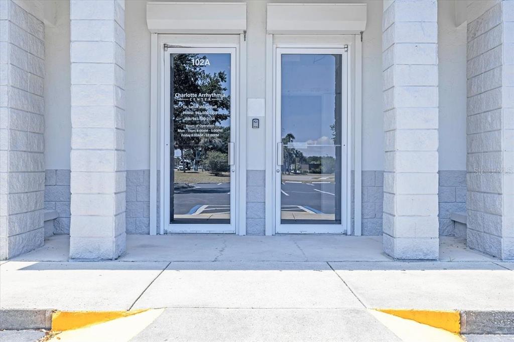 The exterior view shows two glass entrance doors with signage for a medical office — 3300 TAMIAMI TRAIL UNIT 2, PORT CHARLOTTE, FL