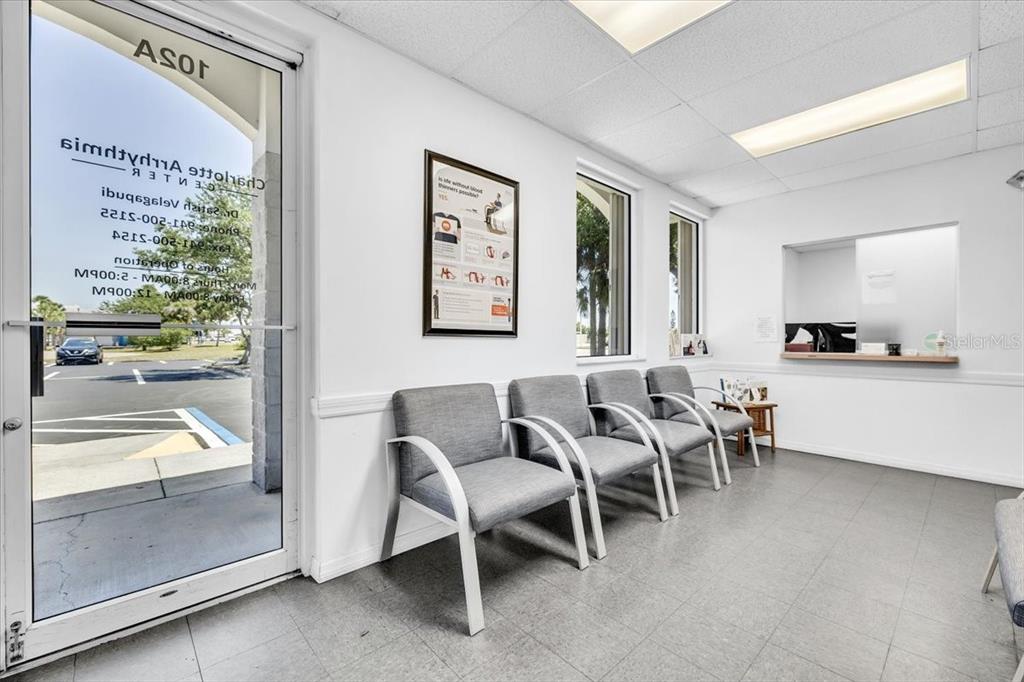 A waiting room features gray chairs, a reception window, and a glass door to parking — 3300 TAMIAMI TRAIL UNIT 2, PORT CHARLOTTE, FL