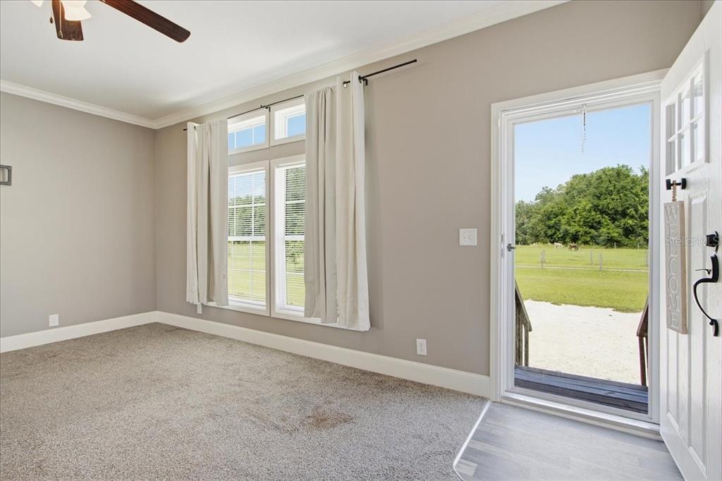 A carpeted room with gray walls, large windows, and a door opening to a pasture — 6731 CR 614, BUSHNELL, FL