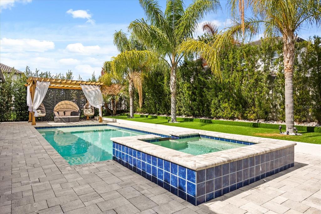 A backyard features a swimming pool, a raised hot tub, a pergola, and palm trees — 8109 LUDINGTON CIRCLE, ORLANDO, FL