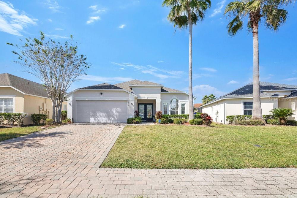 A single-story house with a paved driveway, a two-car garage, and two tall palm trees — 4806 CUMBRIAN LAKES DRIVE, KISSIMMEE, FL