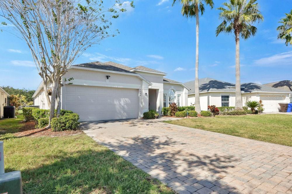 A single-story house with a beige stucco exterior, a two-car garage, and a paved driveway — 4806 CUMBRIAN LAKES DRIVE, KISSIMMEE, FL