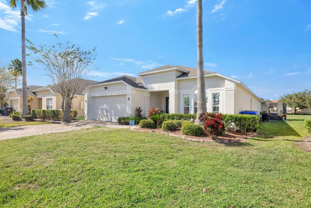 A single-story suburban house with a two-car garage, palm trees, and a manicured lawn — 4806 CUMBRIAN LAKES DRIVE, KISSIMMEE, FL