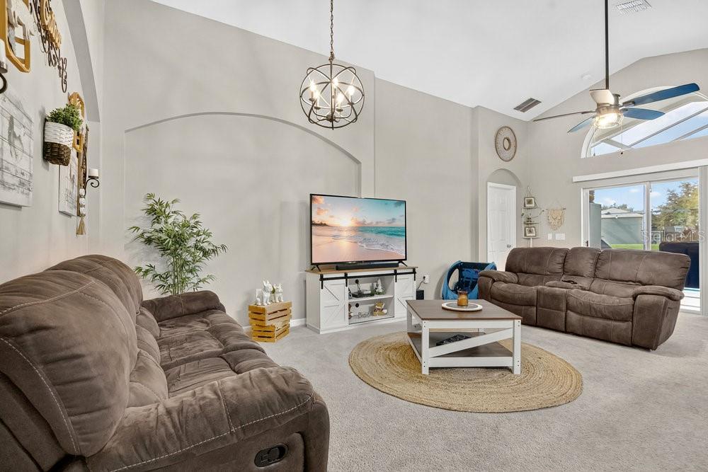 A living room features two brown reclining sofas, a television on a console, and carpeting — 4806 CUMBRIAN LAKES DRIVE, KISSIMMEE, FL