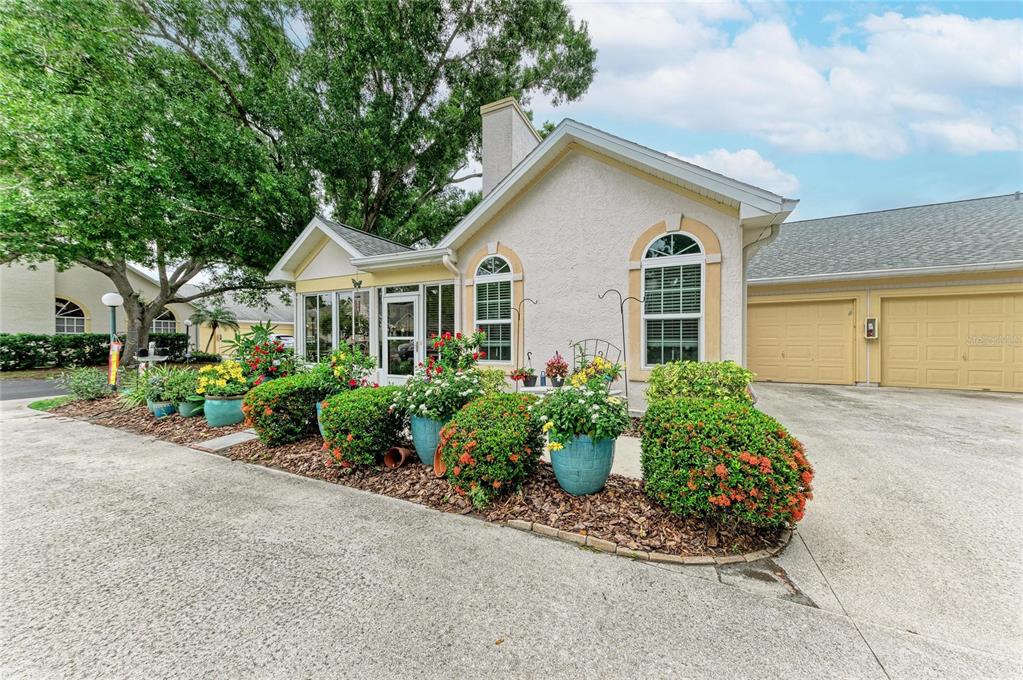 A light-colored house exterior features a front garden with potted plants and a garage — 4512 CITATION LANE UNIT D, SARASOTA, FL