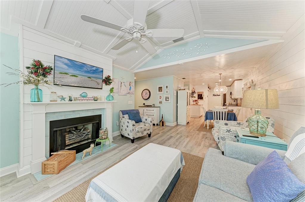 A coastal-style living room features a fireplace, shiplap walls, and an open floor plan — 4512 CITATION LANE UNIT D, SARASOTA, FL