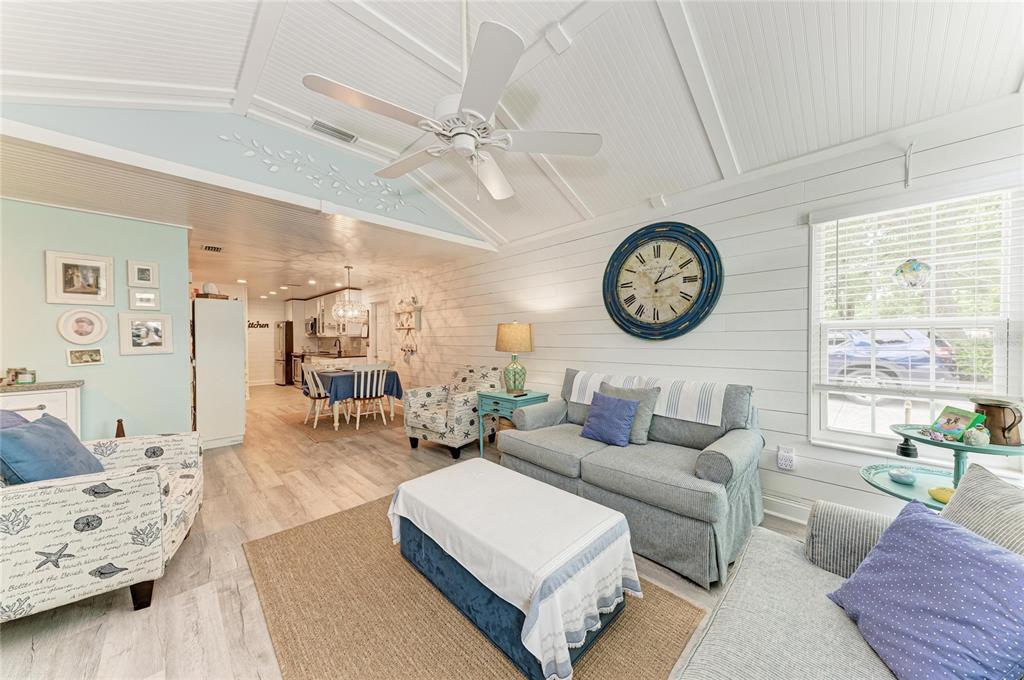 A living room with white shiplap walls, a ceiling fan, and an adjacent dining area — 4512 CITATION LANE UNIT D, SARASOTA, FL