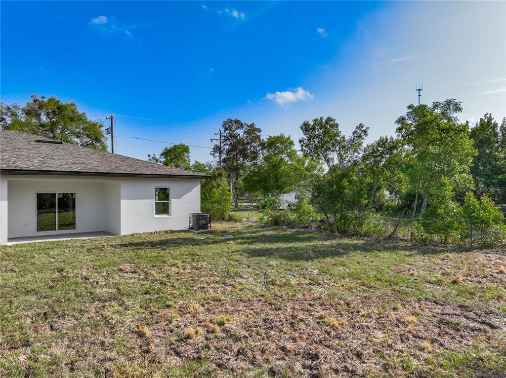 A white house exterior features a sliding glass door, a window, and a grassy backyard — 356 W 4TH STREET, APOPKA, FL