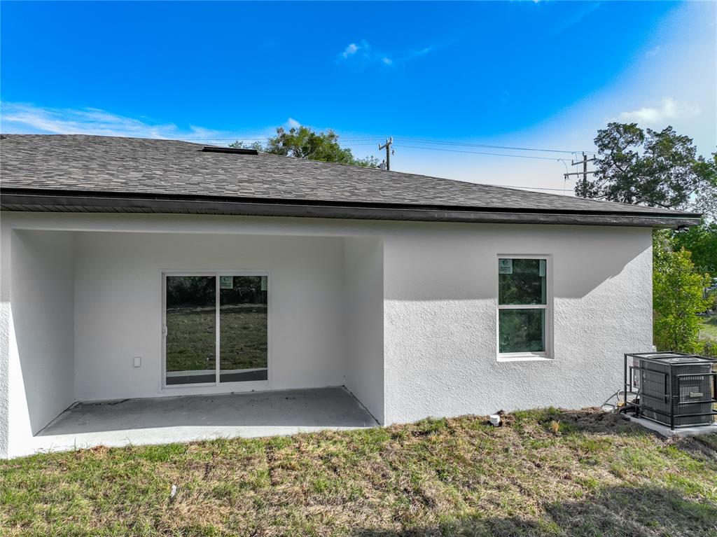 The rear exterior of a white stucco house features a covered patio and an air conditioner — 356 W 4TH STREET, APOPKA, FL