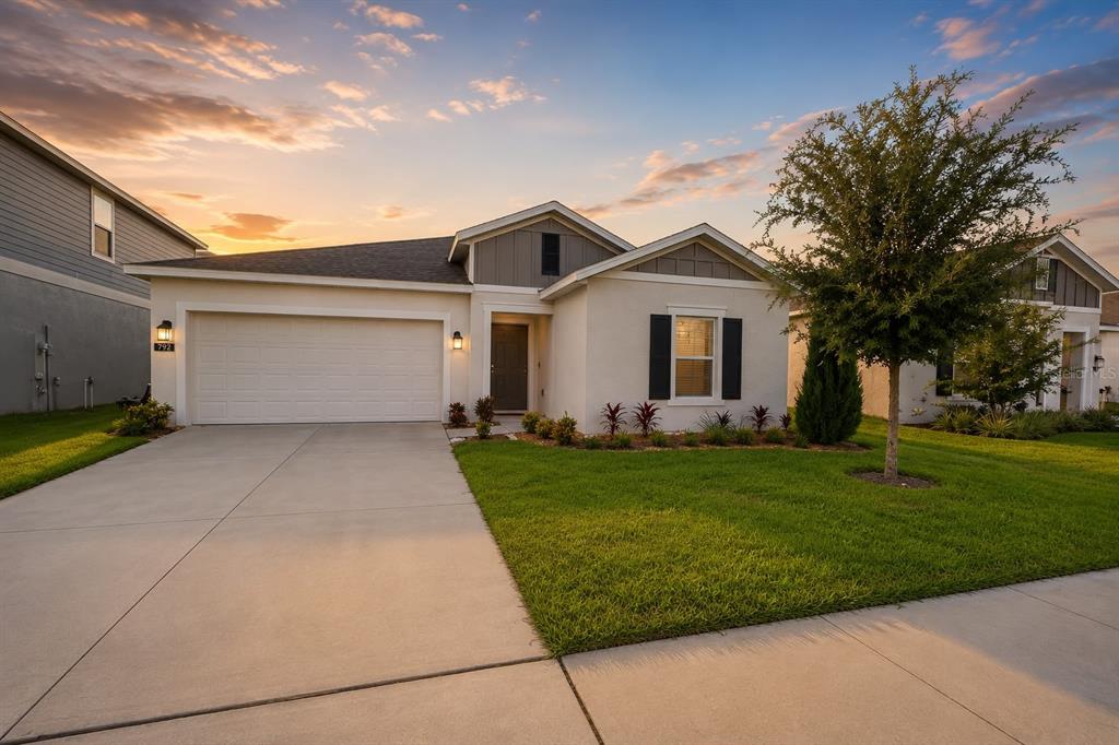 A single-story house with a white stucco exterior, two-car garage, and a manicured front lawn — 792 REGGIE ROAD, WINTER HAVEN, FL