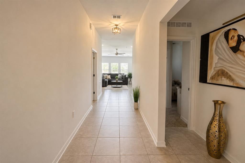 A tiled hallway leads from the entryway toward a living room with a ceiling fan — 792 REGGIE ROAD, WINTER HAVEN, FL