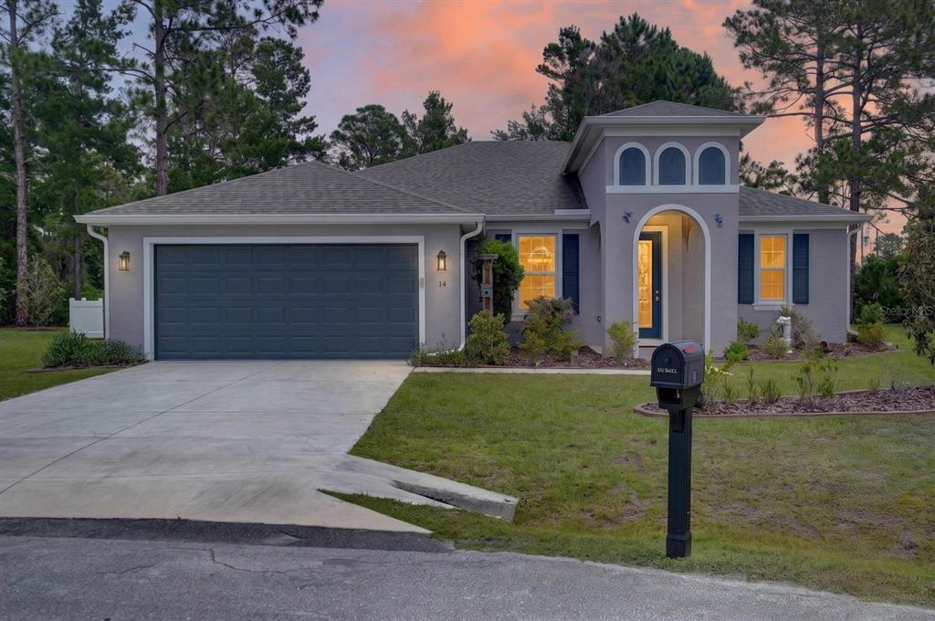 A single-story gray house with a two-car garage and an arched entryway at dusk — 14 SEVILLE PLACE, PALM COAST, FL