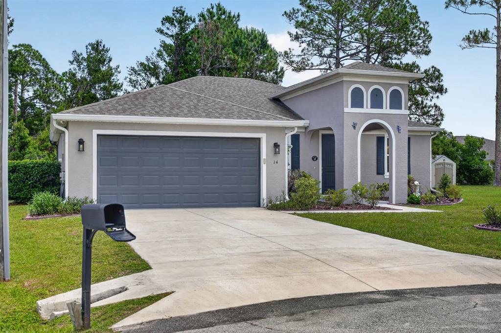 A gray single-story house with a two-car garage, arched entryway, and a concrete driveway — 14 SEVILLE PLACE, PALM COAST, FL
