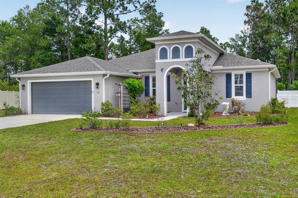 A single-story gray house with a two-car garage and a front arched entryway — 14 SEVILLE PLACE, PALM COAST, FL