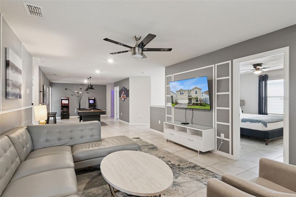 A living room with a gray sectional, pool table, and a television mounted on the wall — 3621 LILY LANE, DAVENPORT, FL