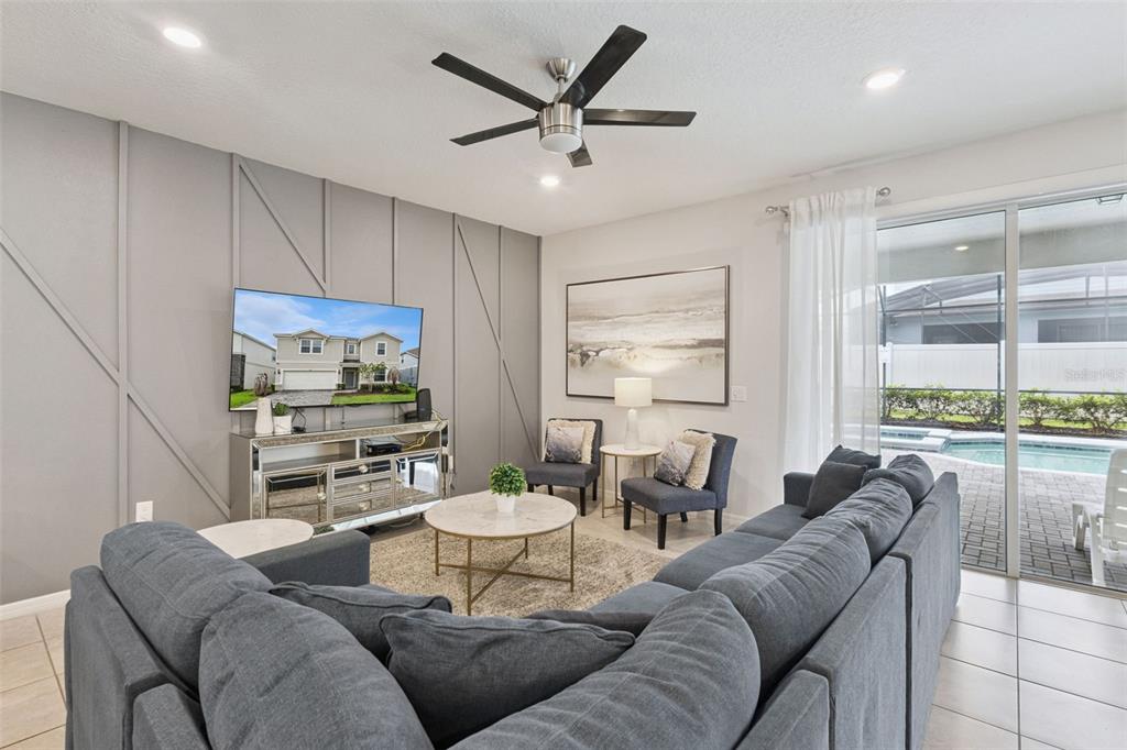 A living room features a gray sectional sofa, a mirrored media console, and a paneled wall — 3621 LILY LANE, DAVENPORT, FL
