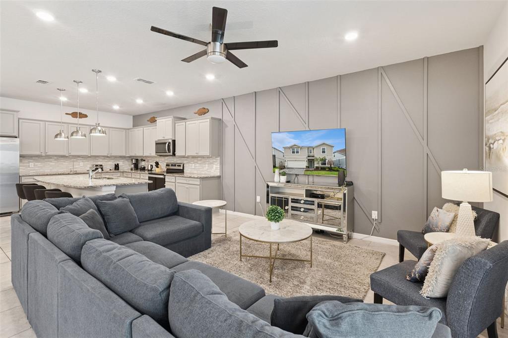 A living room with a gray sectional, accent wall, and an open kitchen with island — 3621 LILY LANE, DAVENPORT, FL