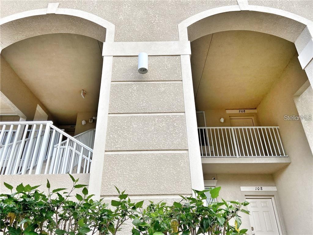 The exterior view shows two stacked apartment entrances with white railings and arched alcoves — 915 FAIRWAYCOVE LANE UNIT 208, BRADENTON, FL