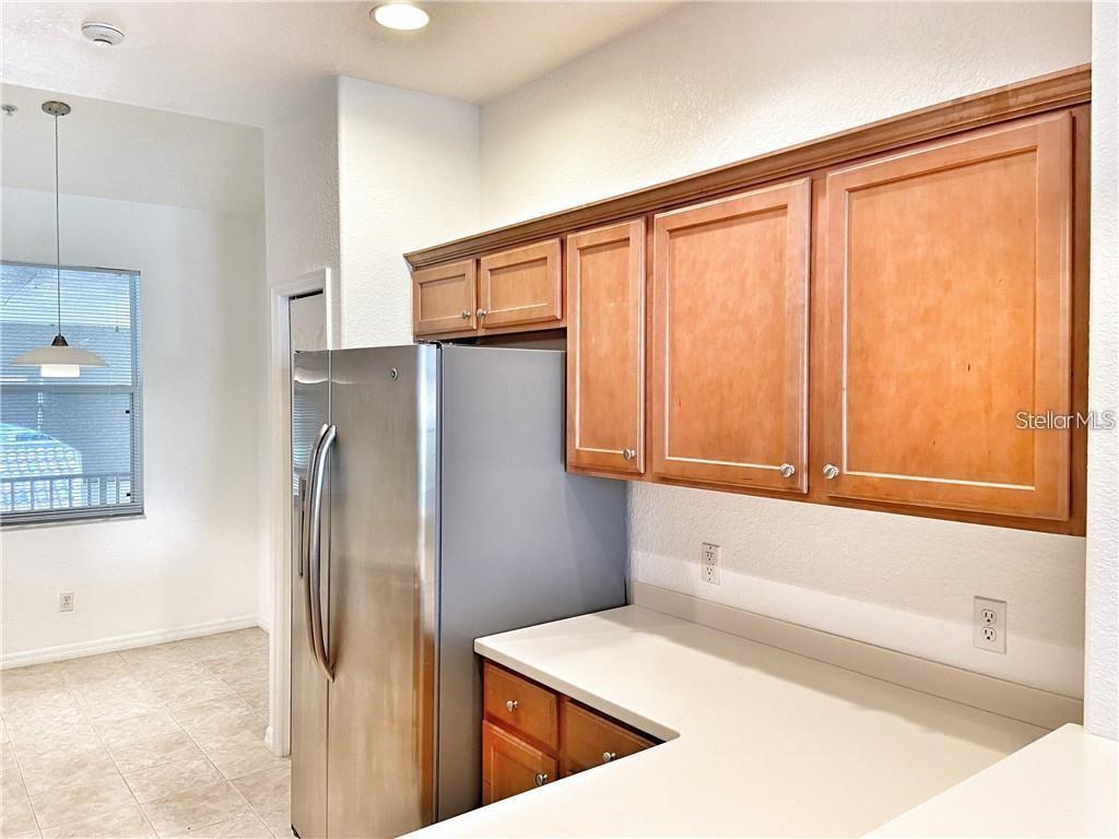 A kitchen features wood cabinets, a stainless steel refrigerator, and white countertops — 915 FAIRWAYCOVE LANE UNIT 208, BRADENTON, FL
