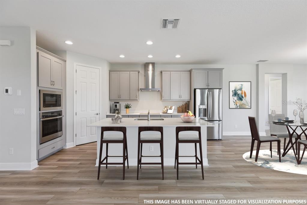 This is a virtually staged rendering of a modern kitchen with gray cabinetry and an island — 9711 SURREY ROSE DRIVE, SAN ANTONIO, FL