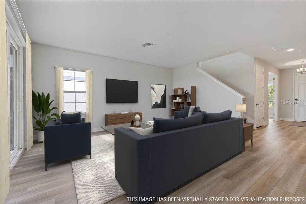 This is a virtually staged living room with light wood flooring and a staircase — 9711 SURREY ROSE DRIVE, SAN ANTONIO, FL