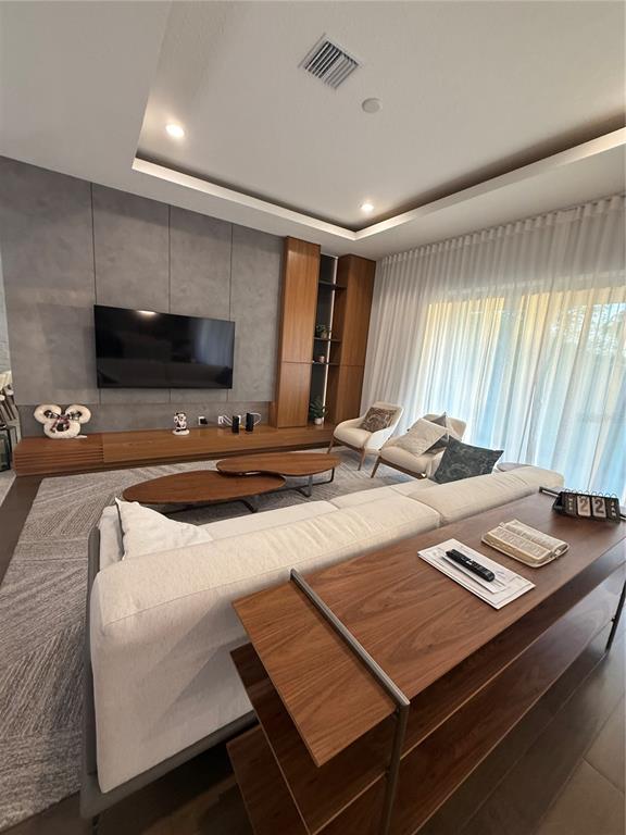 A living room features a large sectional sofa, wood coffee tables, and a media wall — 8289 TOPSAIL PLACE, WINTER GARDEN, FL