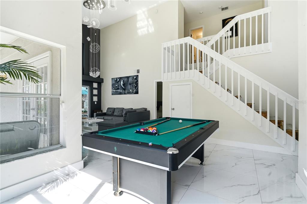 A room with a pool table, white tile floors, and a staircase with white railings — 2724 EMERSON LANE, KISSIMMEE, FL