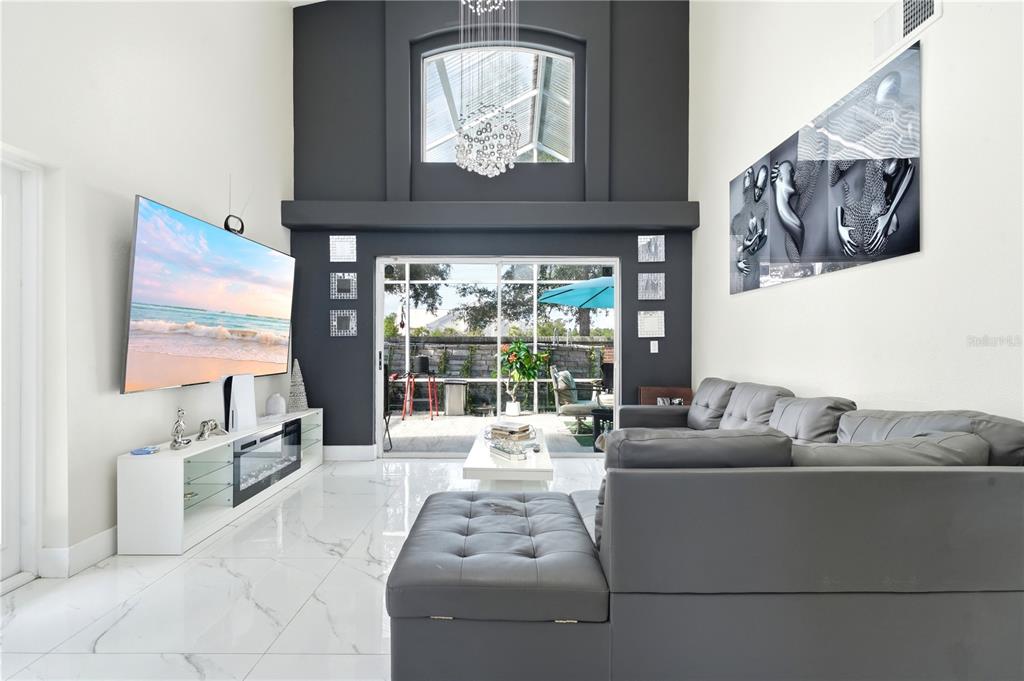 A living room features a gray sectional sofa, a large television, and a high ceiling — 2724 EMERSON LANE, KISSIMMEE, FL