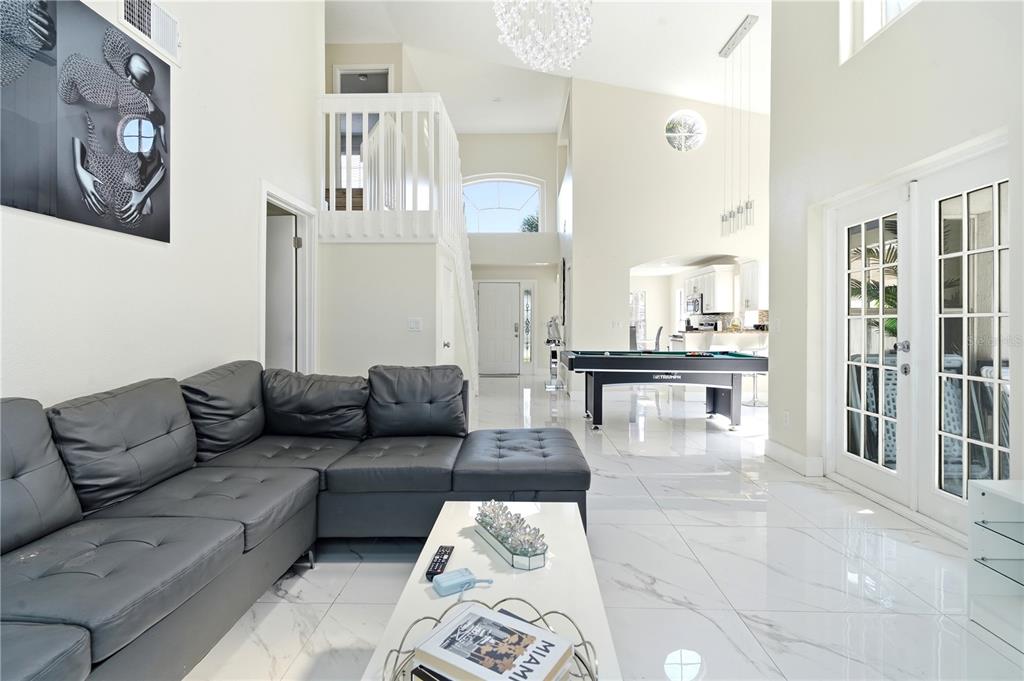 A living room with a grey sectional sofa, a pool table, and white tile flooring — 2724 EMERSON LANE, KISSIMMEE, FL