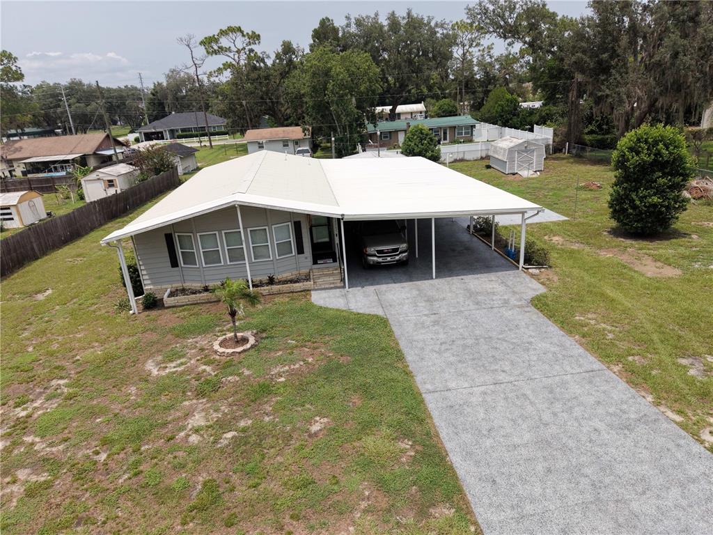An aerial view shows a single-story house with a large attached carport and concrete driveway — 37747 SILVER PINES AVENUE, ZEPHYRHILLS, FL
