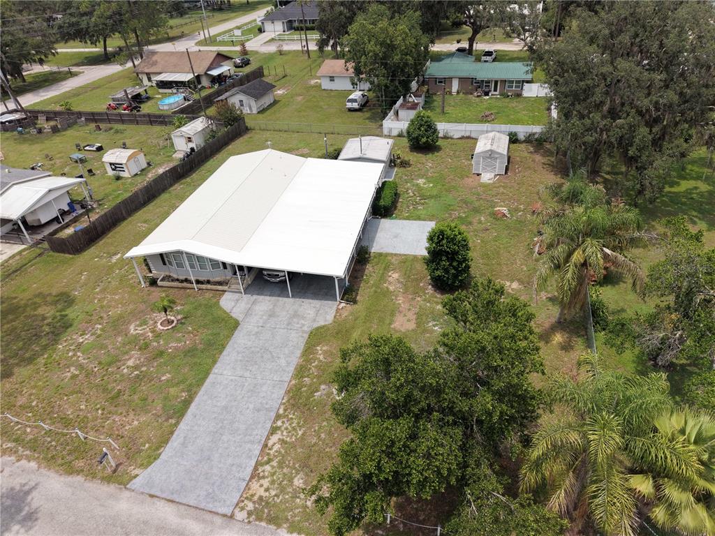 An aerial view shows a single-story house with a large carport and a concrete driveway — 37747 SILVER PINES AVENUE, ZEPHYRHILLS, FL
