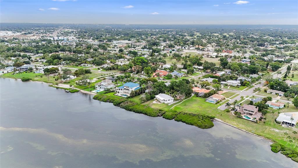 An aerial view shows waterfront houses along a coastline with green lawns and trees — 7538 WESTMORELAND DRIVE, SARASOTA, FL
