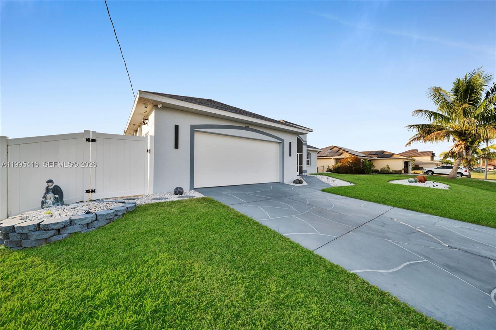 A gray house with a white garage door, a paved driveway, and a white fence — 1024 NW 23, Cape Coral FL 33993, CAPE CORAL, FL