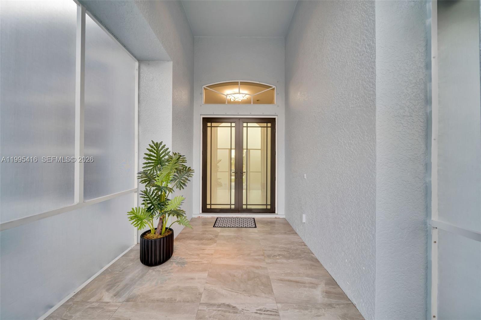 A covered entryway features a double glass door, a potted plant, and tiled flooring — 1024 NW 23, Cape Coral FL 33993, CAPE CORAL, FL