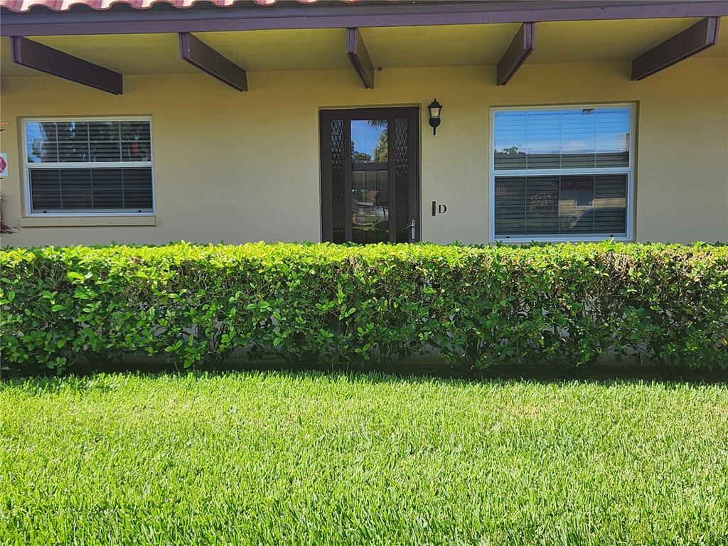 A single-story building exterior features a brown front door labeled D and two windows — 1701 PINEHURST ROAD UNIT 34D, DUNEDIN, FL