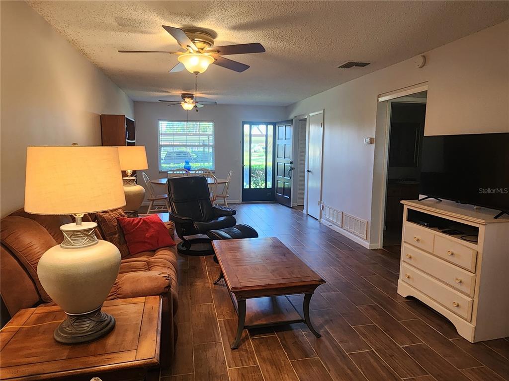 A living room features tile flooring, a ceiling fan, a coffee table, and a television — 1701 PINEHURST ROAD UNIT 34D, DUNEDIN, FL