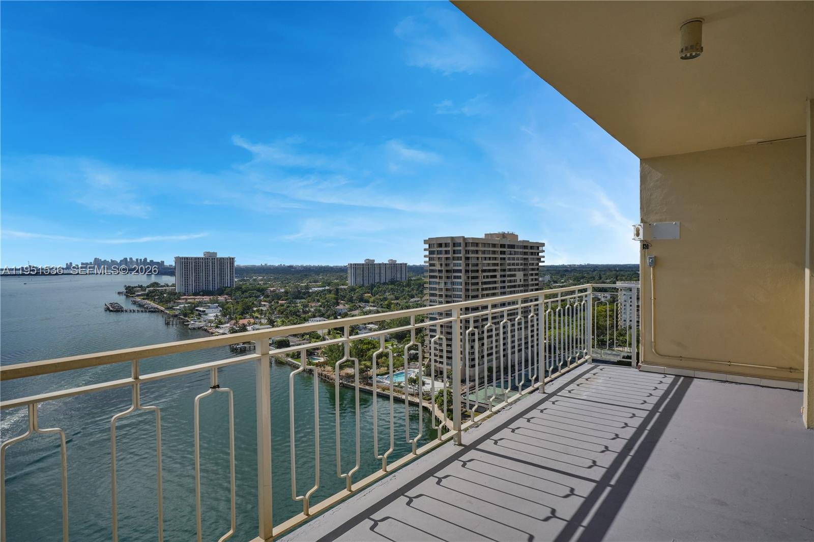 A high-rise balcony overlooks a bay with surrounding apartment buildings and lush greenery — 11111 Biscayne Blvd # 21C, Miami FL 33181, MIAMI, FL