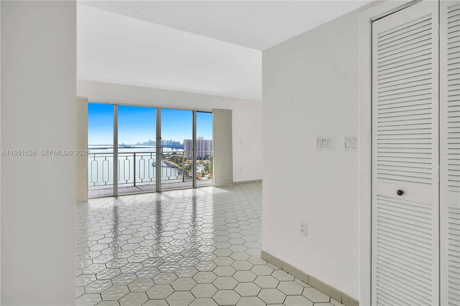 A bright room features white hexagonal floor tiles, white walls, and a balcony with water views — 11111 Biscayne Blvd # 21C, Miami FL 33181, MIAMI, FL