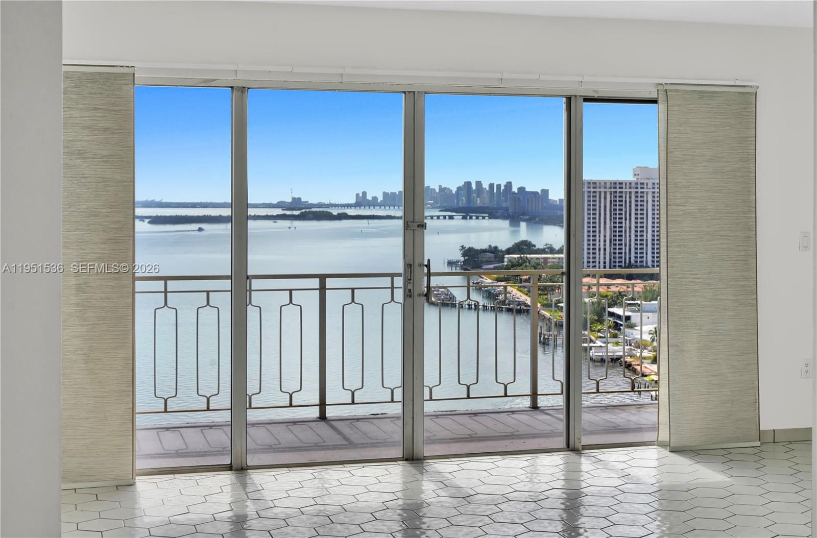A room with white hexagonal tile flooring features a large sliding glass door overlooking water — 11111 Biscayne Blvd # 21C, Miami FL 33181, MIAMI, FL