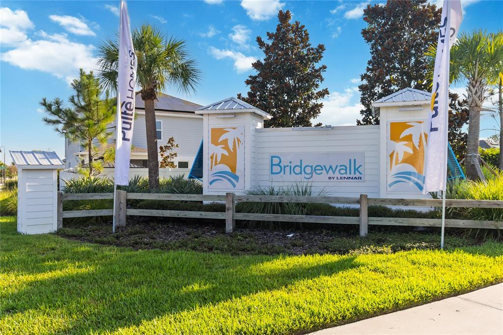 A white community entrance sign for Bridgewalk by Lennar stands behind a wooden fence — 5512 FIONA LANE, ST CLOUD, FL