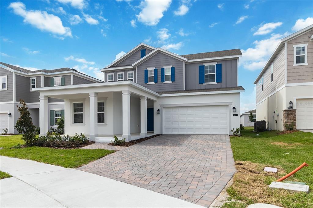 A two-story suburban house with a covered front porch, gray siding, and a paved driveway — 5512 FIONA LANE, ST CLOUD, FL