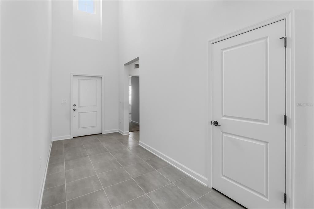 An entryway features gray tile flooring, white walls, and a high ceiling with a window — 5512 FIONA LANE, ST CLOUD, FL