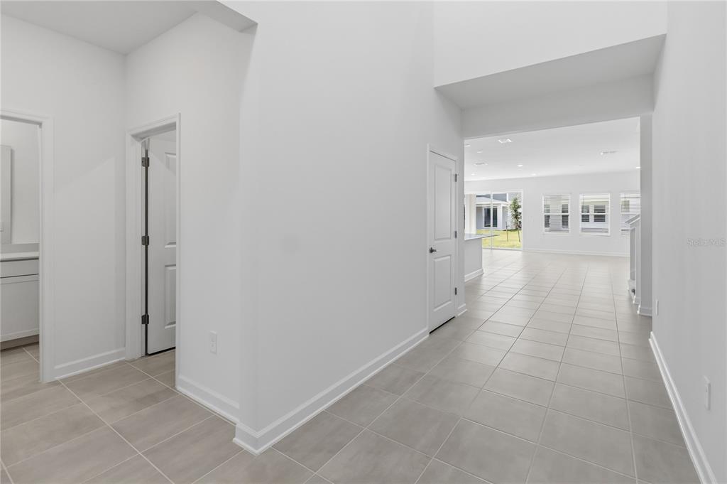 A bright hallway with light tile flooring leads into an open-concept living area — 5512 FIONA LANE, ST CLOUD, FL