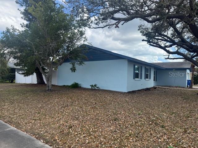 A light blue house with a dark roof stands on a lawn covered in leaves — 3401 50TH STREET W, BRADENTON, FL