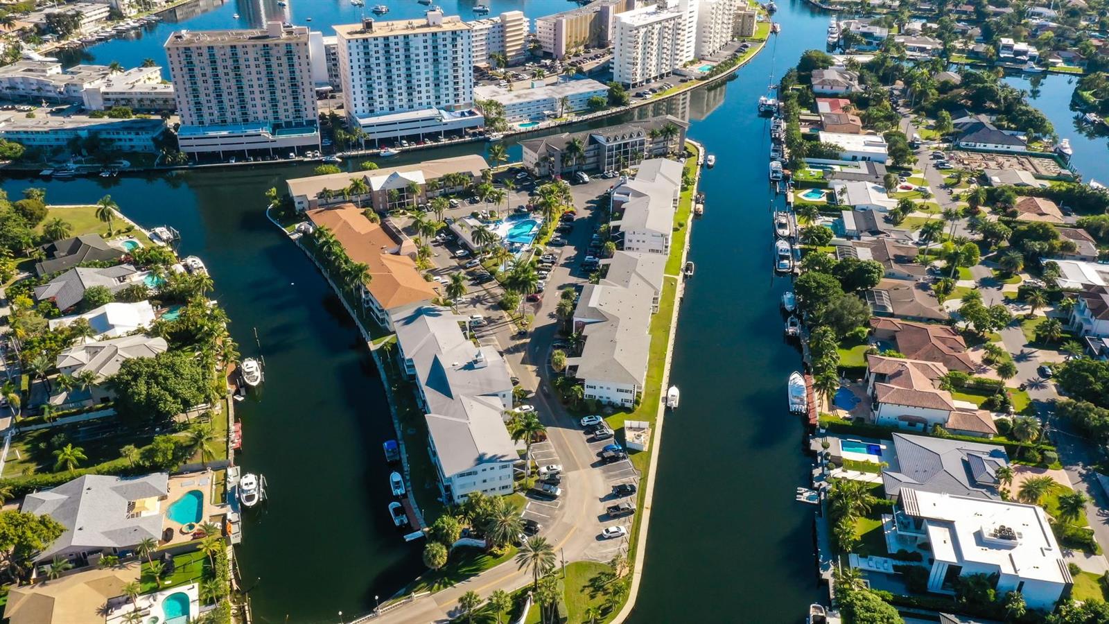 An aerial view shows residential buildings and houses situated along narrow canals with docked boats — 450 Paradise Isle Boulevard, Hallandale Beach FL 33009, HALLANDALE BEACH, FL